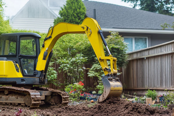 Excavator digging in backyard garden